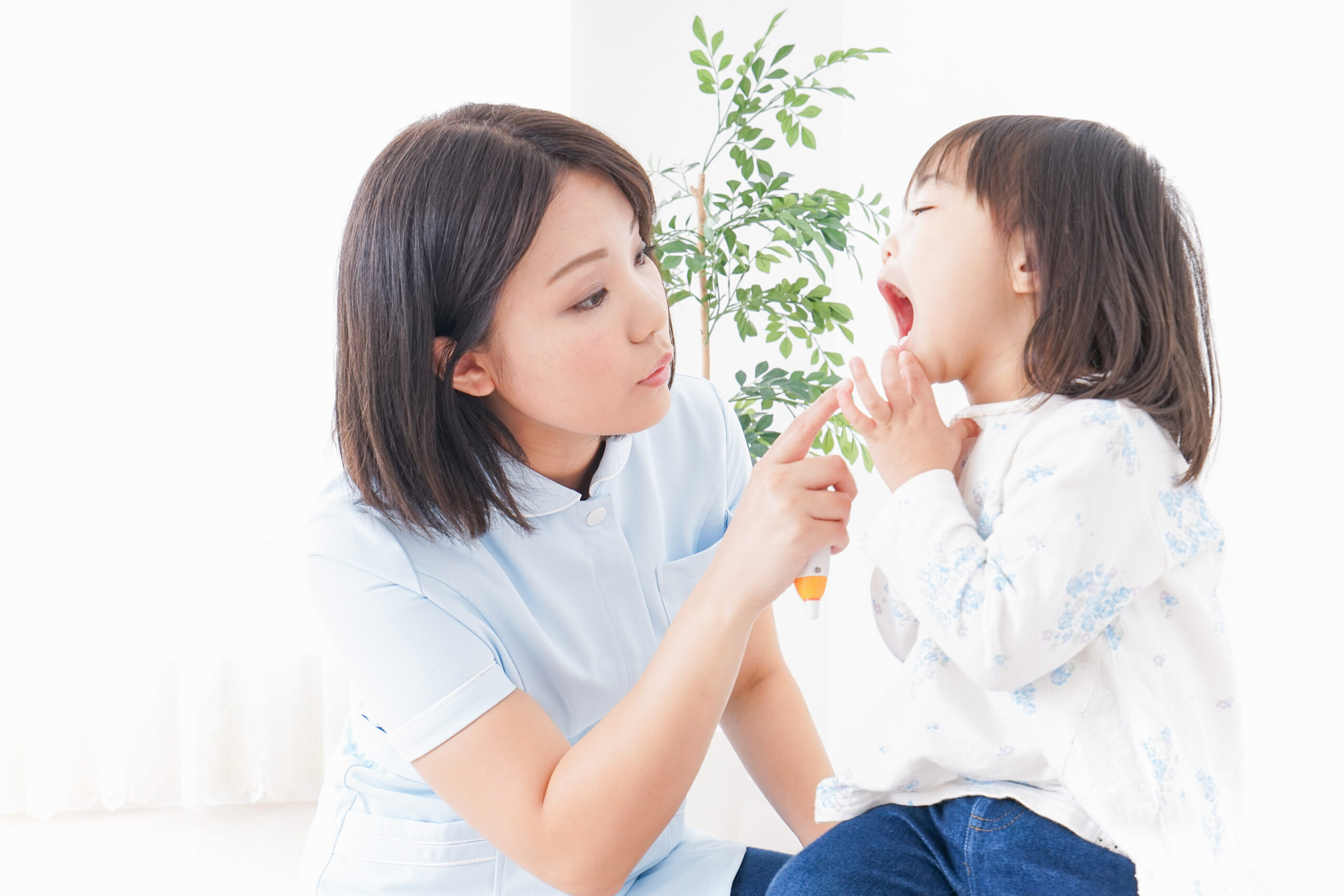 女性が子供の口の中を見ている様子